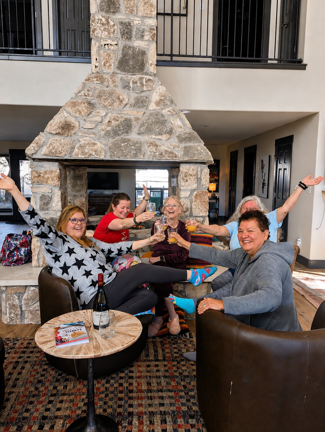 Friends raising glasses by the fireplace at The Gathering