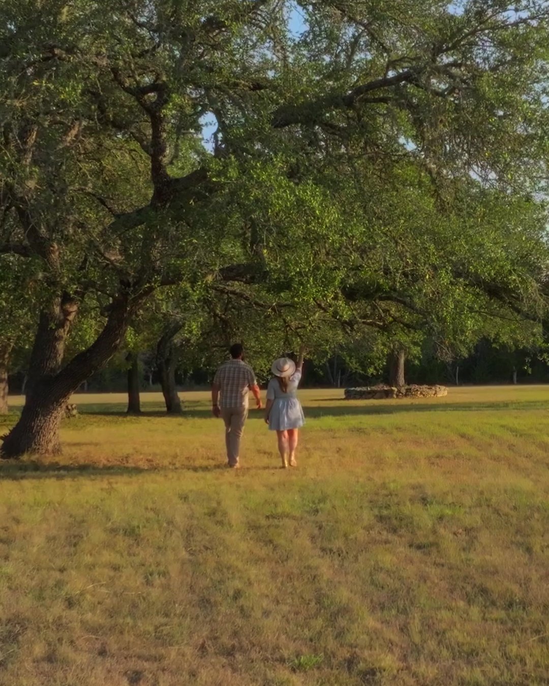 A couple walking beneath the oak trees at The Gathering